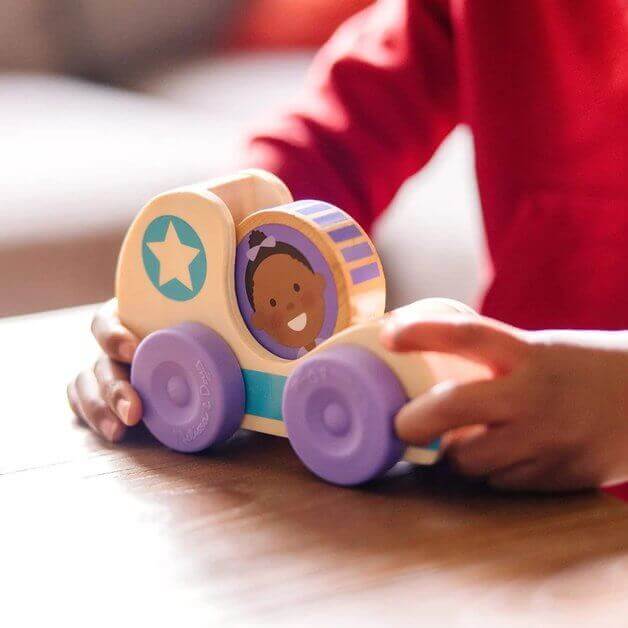 A child playing with the Go Tots Star Car Play Set, a wooden kinetic toy featuring colorful wheels and a double-sided character disk.