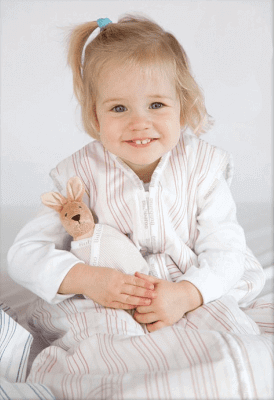Smiling child in a Joey Swag Baby Sleeping Bag holding a soft toy, showcasing comfort and safety.